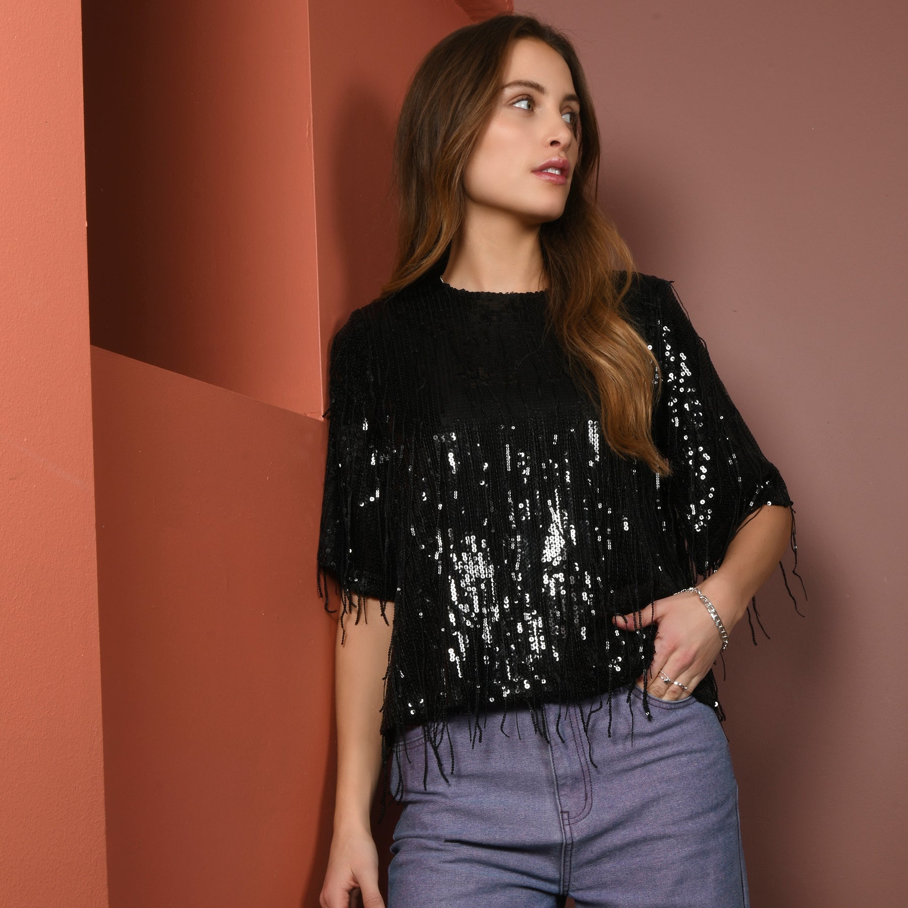 A woman in shiny black top with jeans